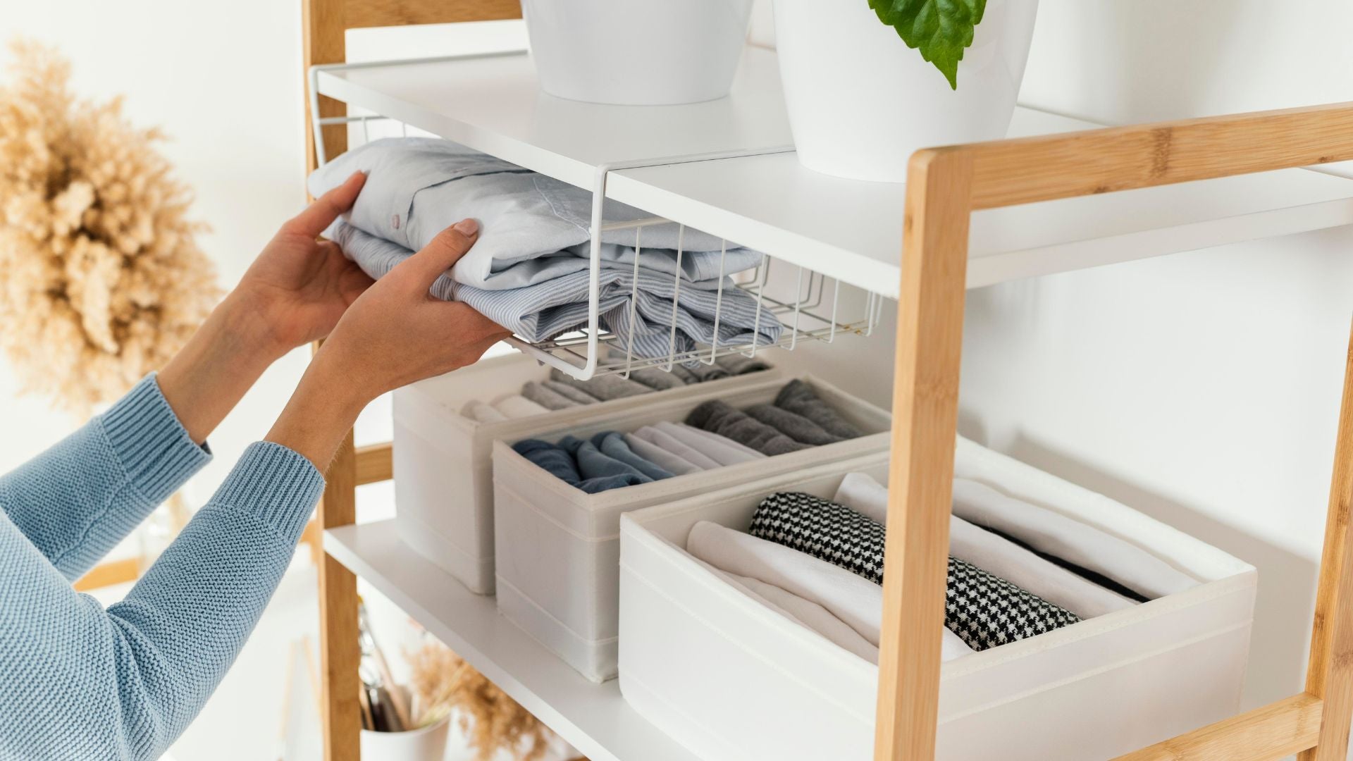 Organized shelf with neatly folded clothes in fabric storage bins — The Neat Nest smart home organization solutions.