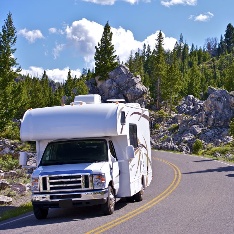 RV driving through scenic mountain road — The Neat Nest essentials for RV and travel living.
