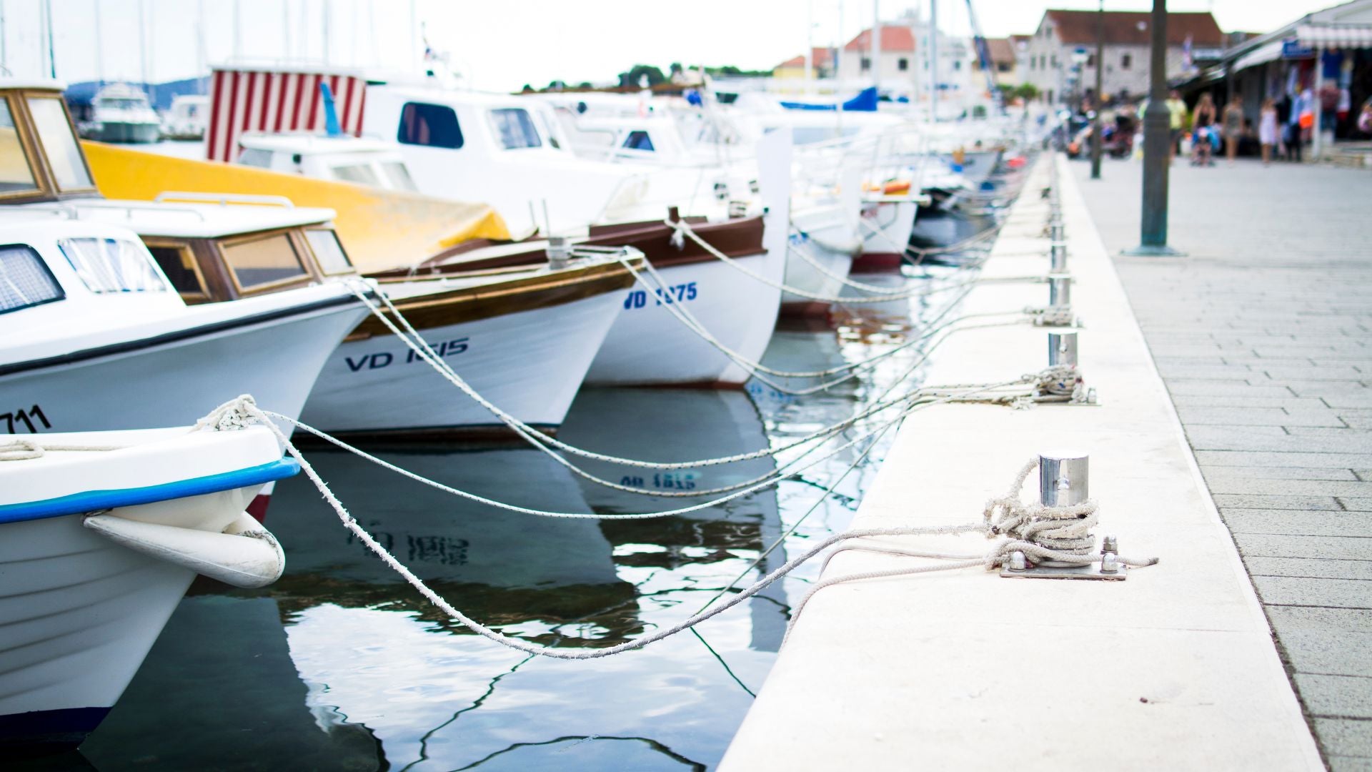 Boats docked at a marina with ropes tied along the pier — The Neat Nest boat living inspiration.